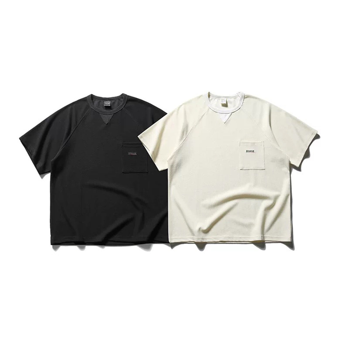 Black and off-white short-sleeve raglan T-shirts shown from the front, each with a chest pocket.