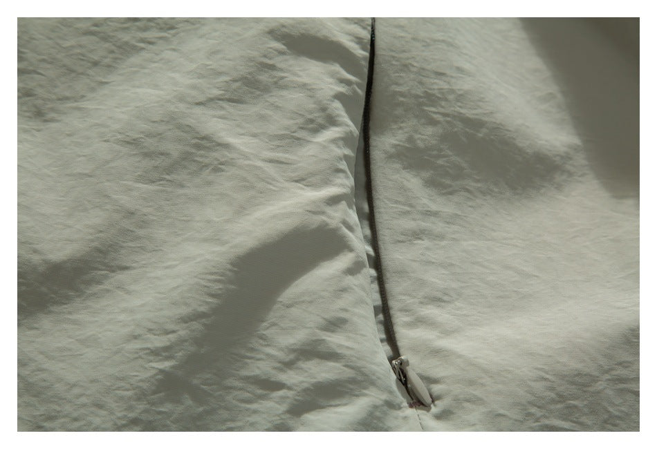 Close-up of the pale sage jacket's front zipper and fabric.