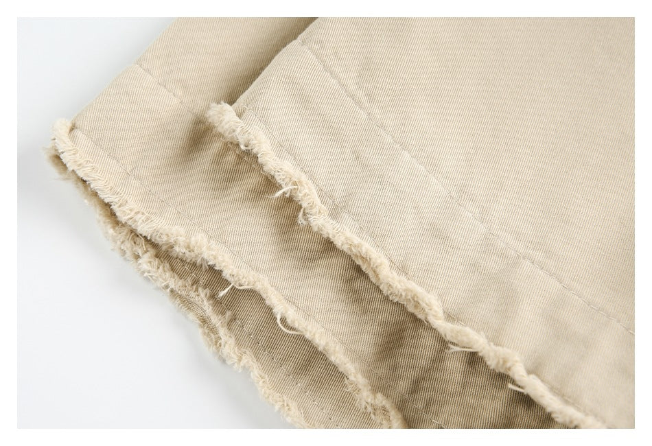 Close-up of layered beige garment edges with frayed raw hems and visible stitching.