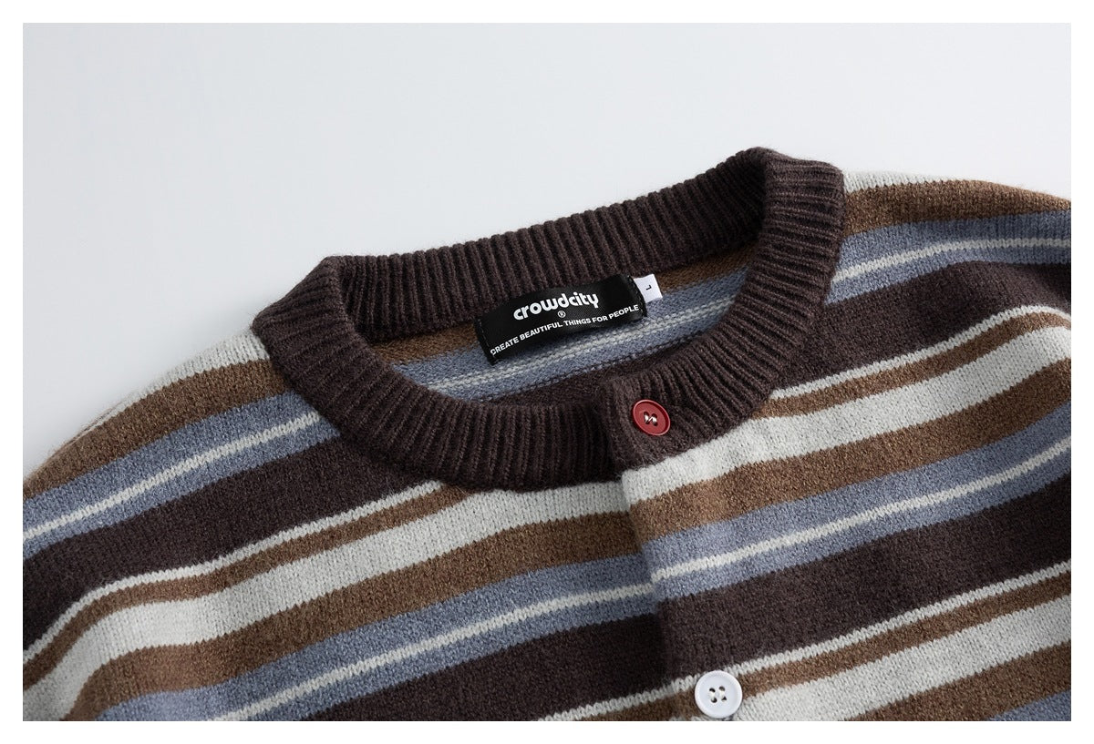 Close-up of a striped knit cardigan neckline with dark ribbing, a red button, and cream, brown, and blue-gray stripes.