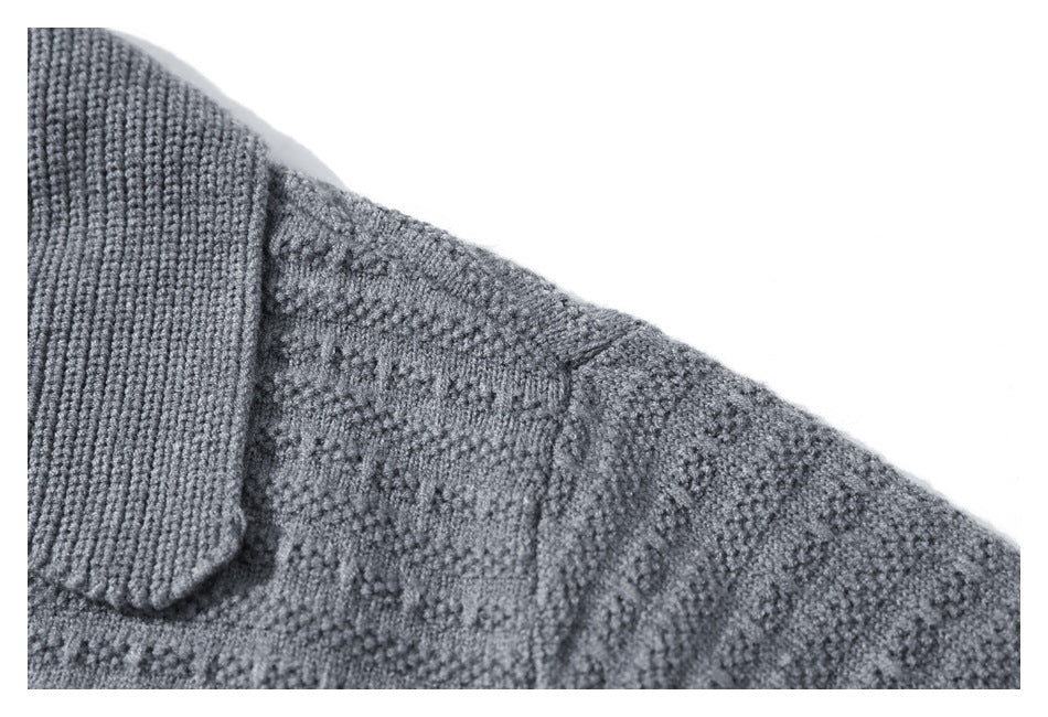 Close-up of a gray textured knit cardigan showing its ribbed collar and shoulder seam.