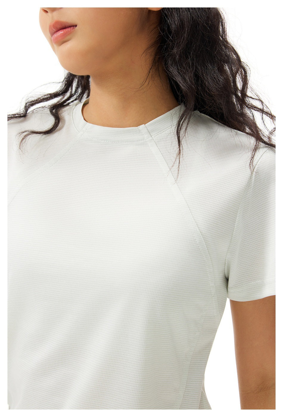 Close-up of an off-white shirt showing its textured fabric, crew neckline, and raglan shoulder seams.