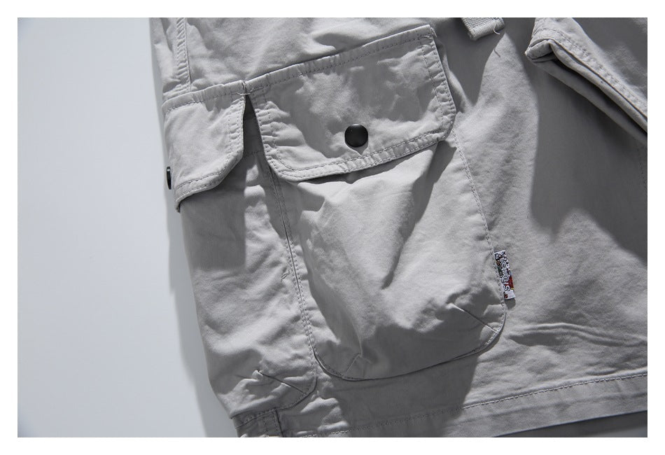 Close-up of a light gray cargo pocket with a snap flap and a small sewn-on decorative label.