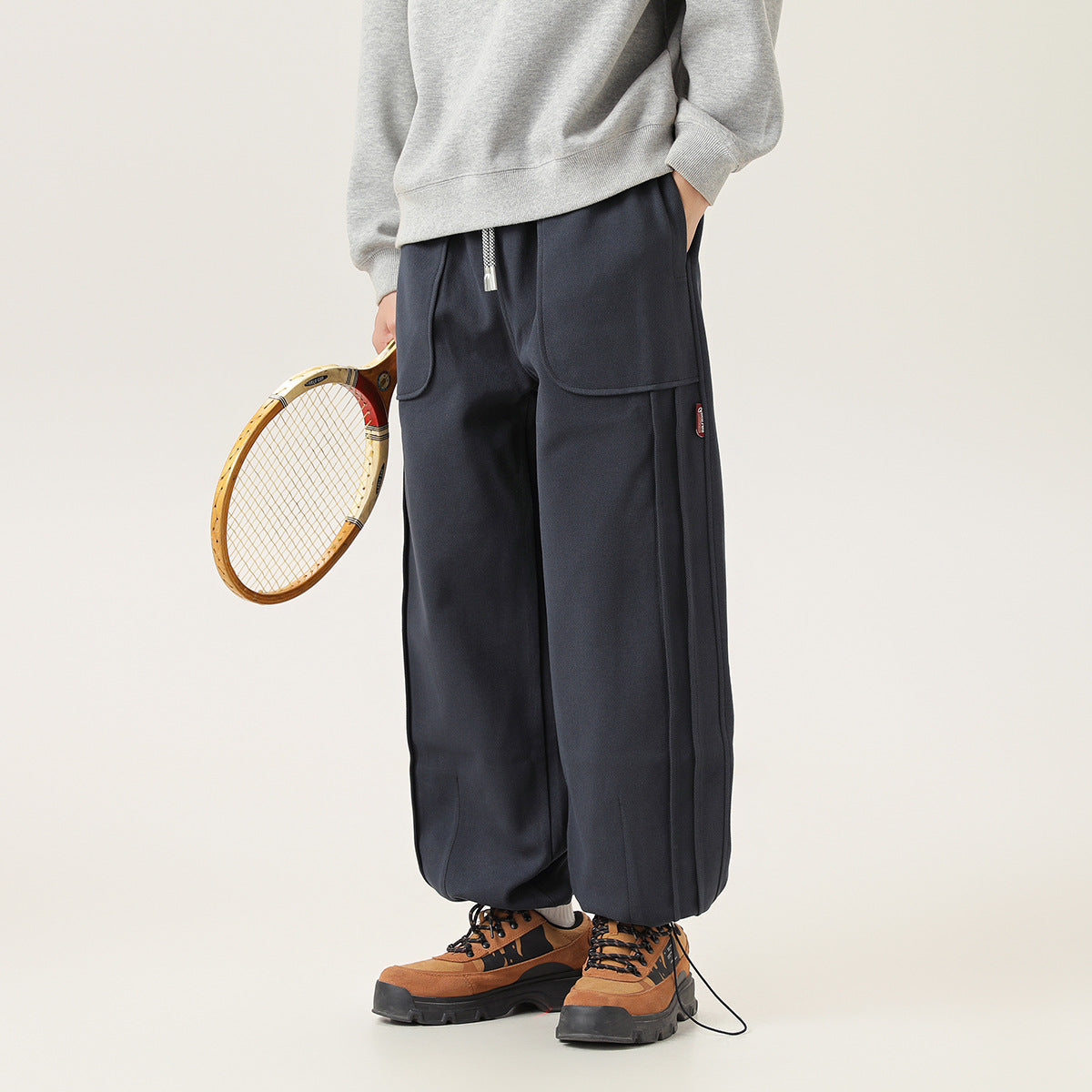Angled front view of a model wearing dark navy drawstring pants with large pockets and gathered cuffs.