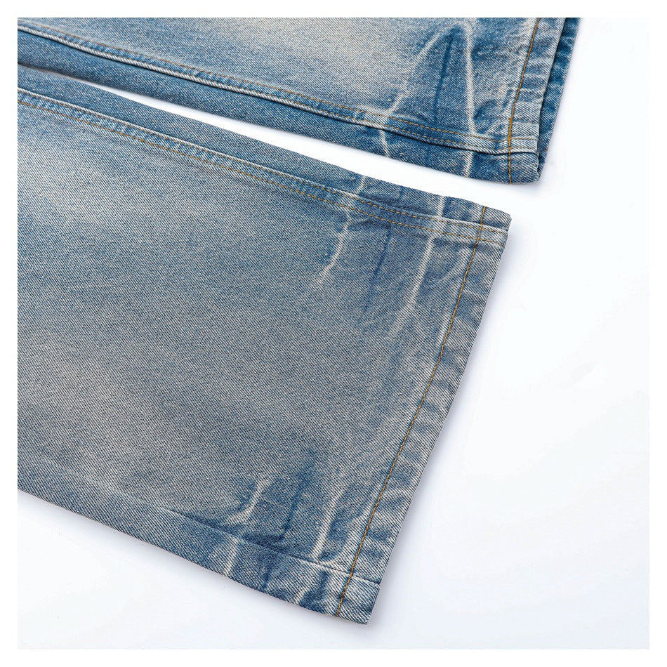 Close-up of the stitched hems on two legs of faded blue jeans.