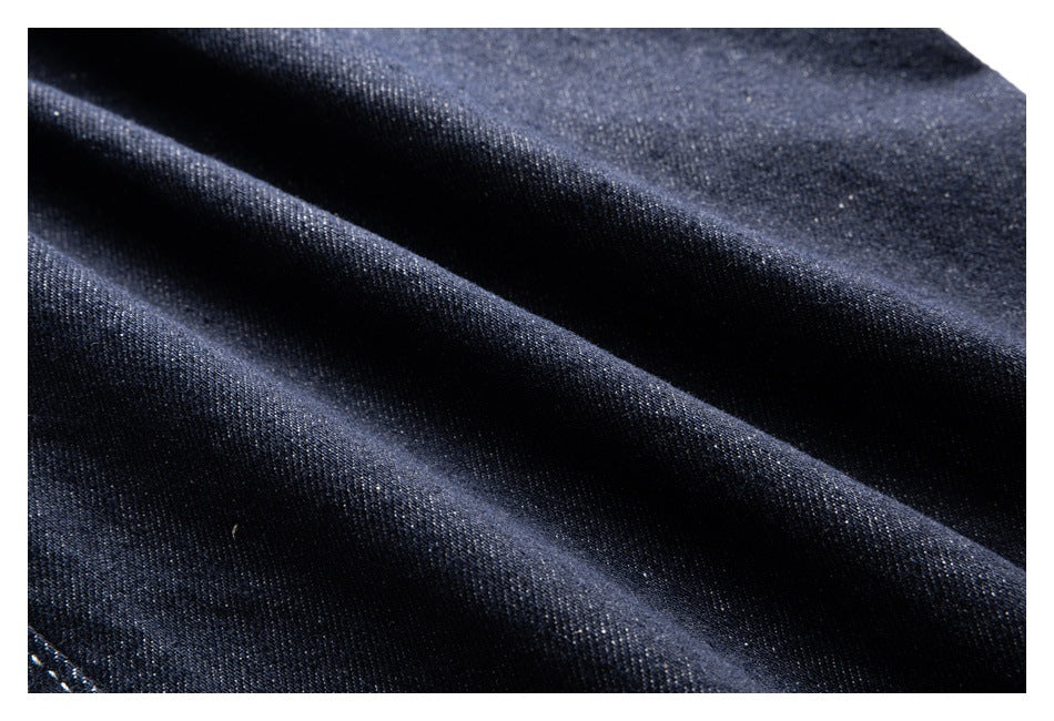 Macro view of dark indigo denim fabric in soft folds, showing its diagonal weave.