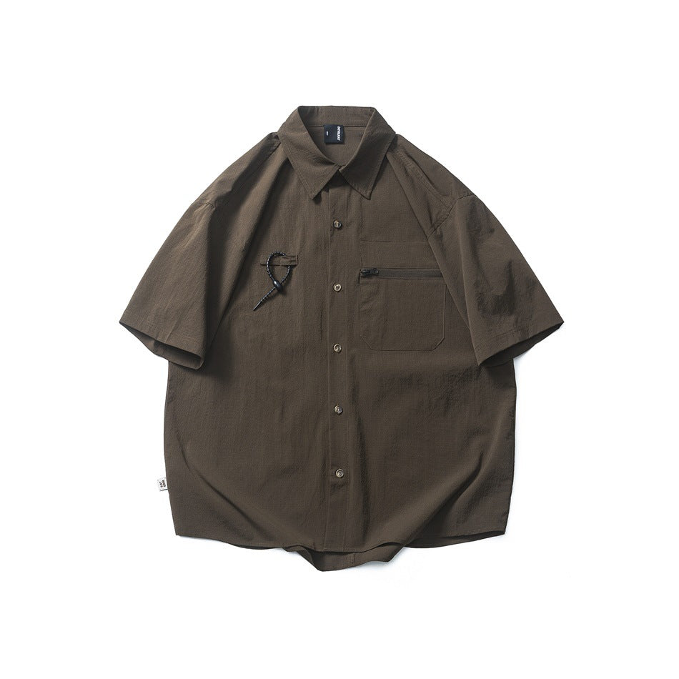 Brown short-sleeve button-up shirt flat lay with chest zip pocket and cord toggle
