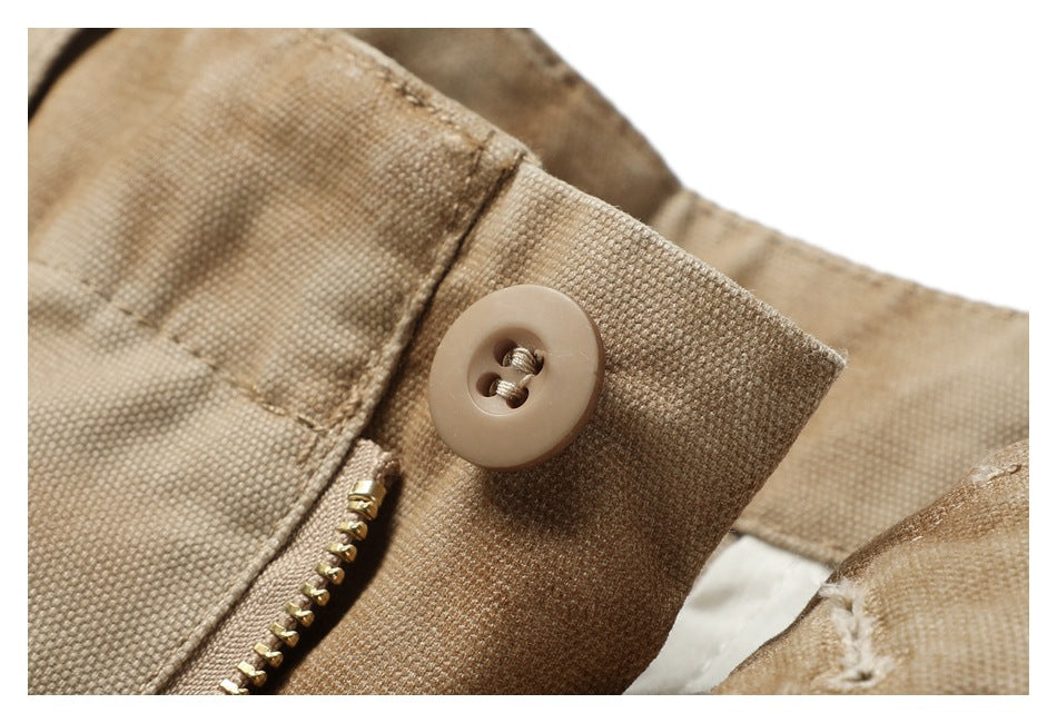 Close-up of a tan button and brass zipper on the mottled pants.