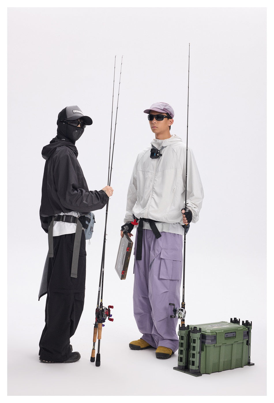Two models in fishing outfits: one wears a white jacket with lavender cargo pants, the other wears black clothing.