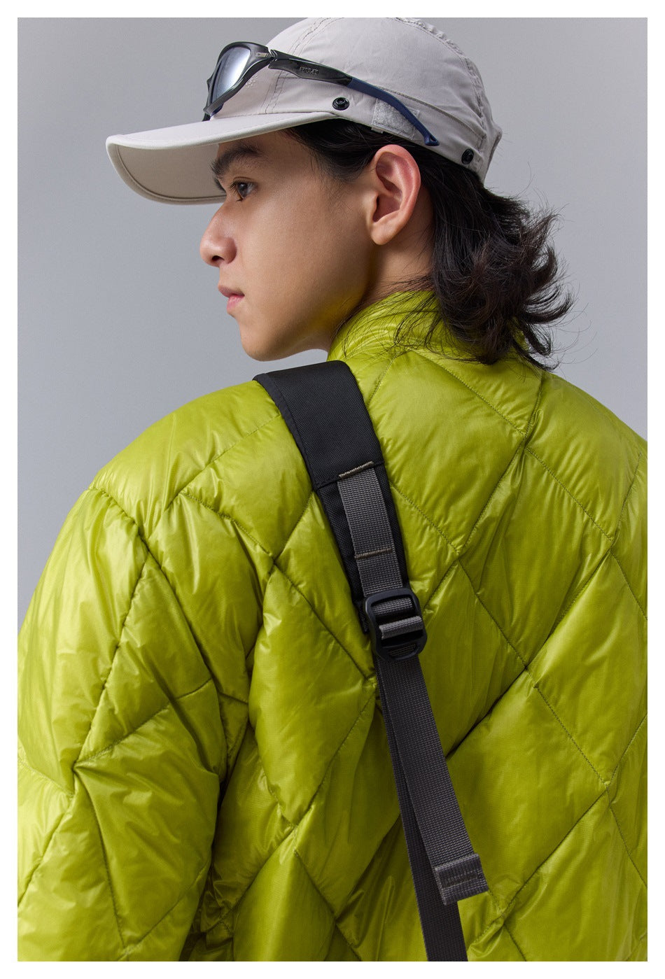 Close-up of the lime-green jacket's diamond-quilted back and shoulder, with a black adjustable strap across it.