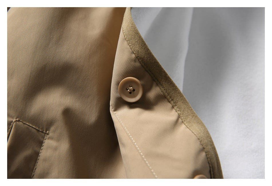 Close-up of a tan jacket button and stitched front placket beside the white lining.