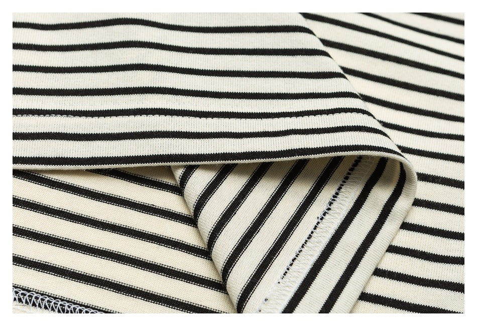 Close-up of black-and-cream striped fabric showing a folded edge and overlock stitching.