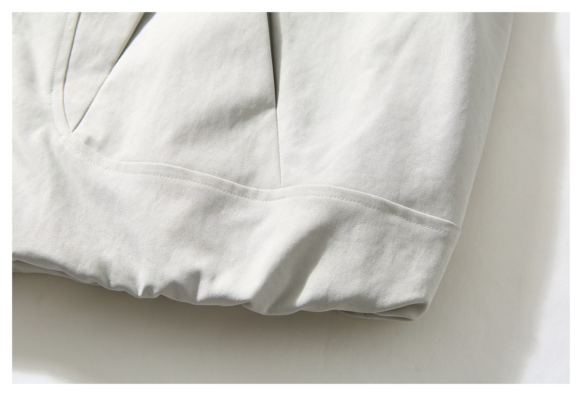 Close-up of the off-white jacket's lower hem and curved panel stitching.