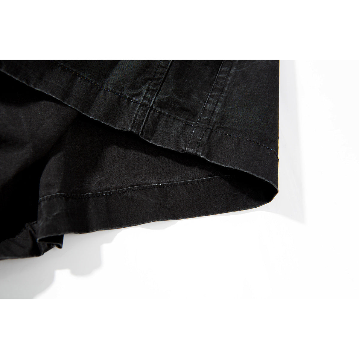 Close-up of the stitched hem and fabric layers on black shorts.