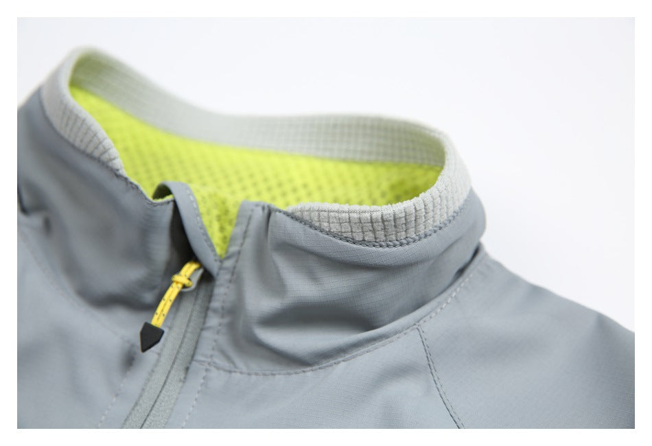 Close-up of a gray jacket's raised collar, showing pale grid-textured trim, neon yellow mesh lining, and a yellow zipper