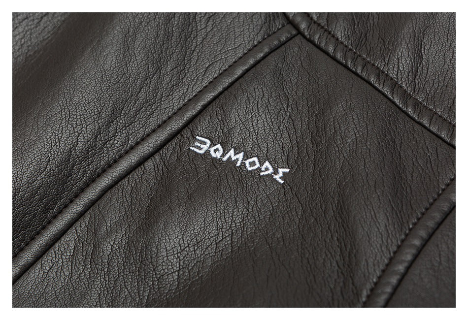 Close-up of a small white embroidered word on a dark brown leather-look jacket panel.
