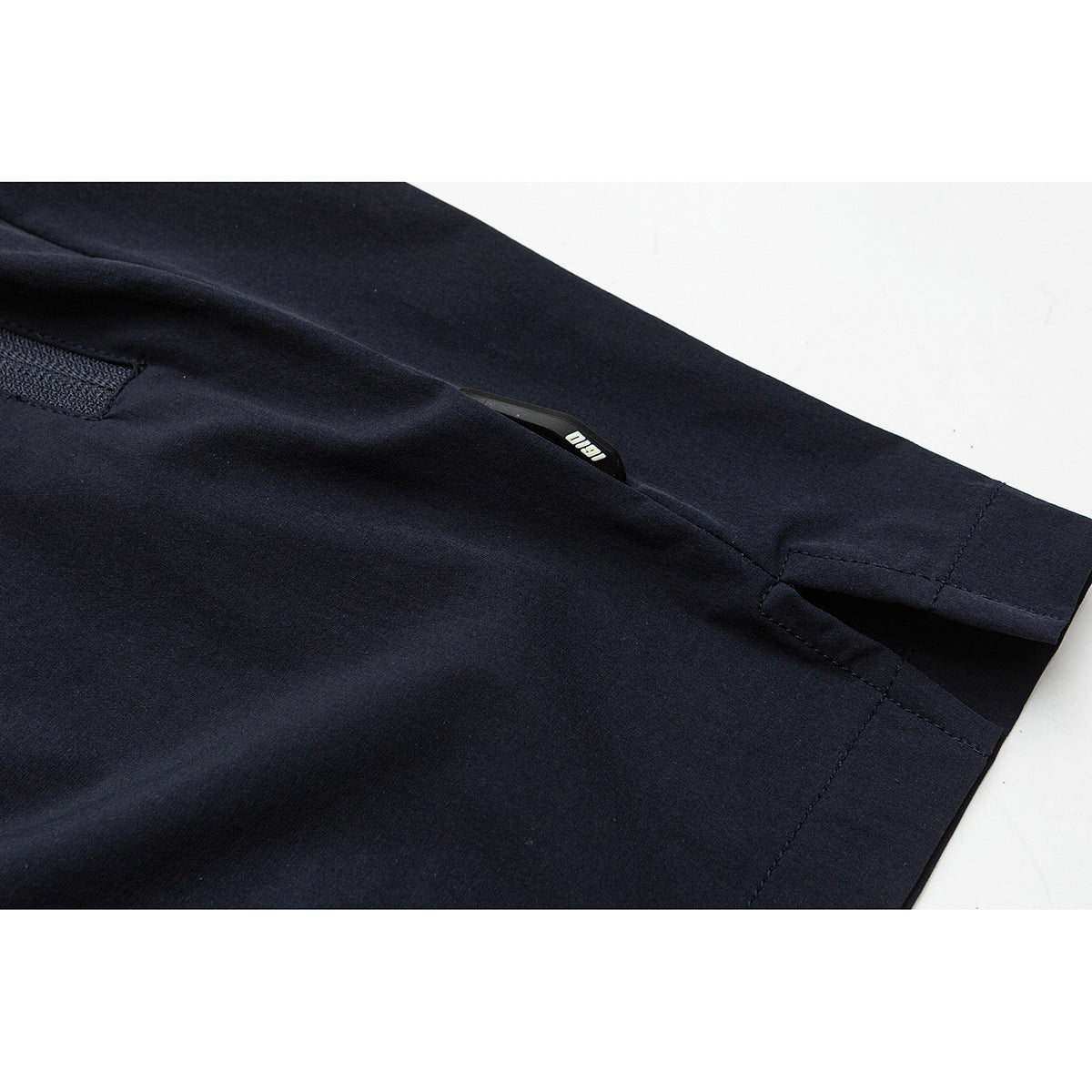 Close-up of a navy pants pocket opening and stitched hem.