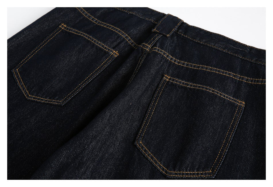 Close view of the back of dark indigo jeans, showing two patch pockets and golden contrast stitching.