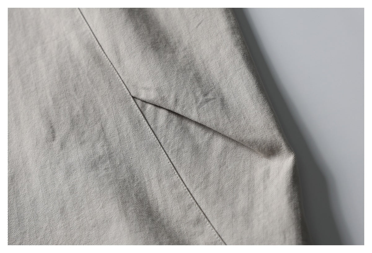 Close-up of gray herringbone trouser fabric and a folded seam detail.