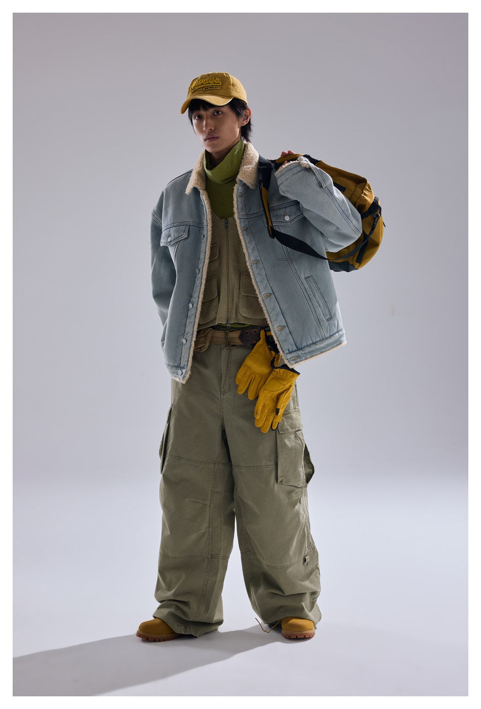 Full-length model wearing a light blue sherpa-lined denim jacket with olive cargo pants and yellow accessories.