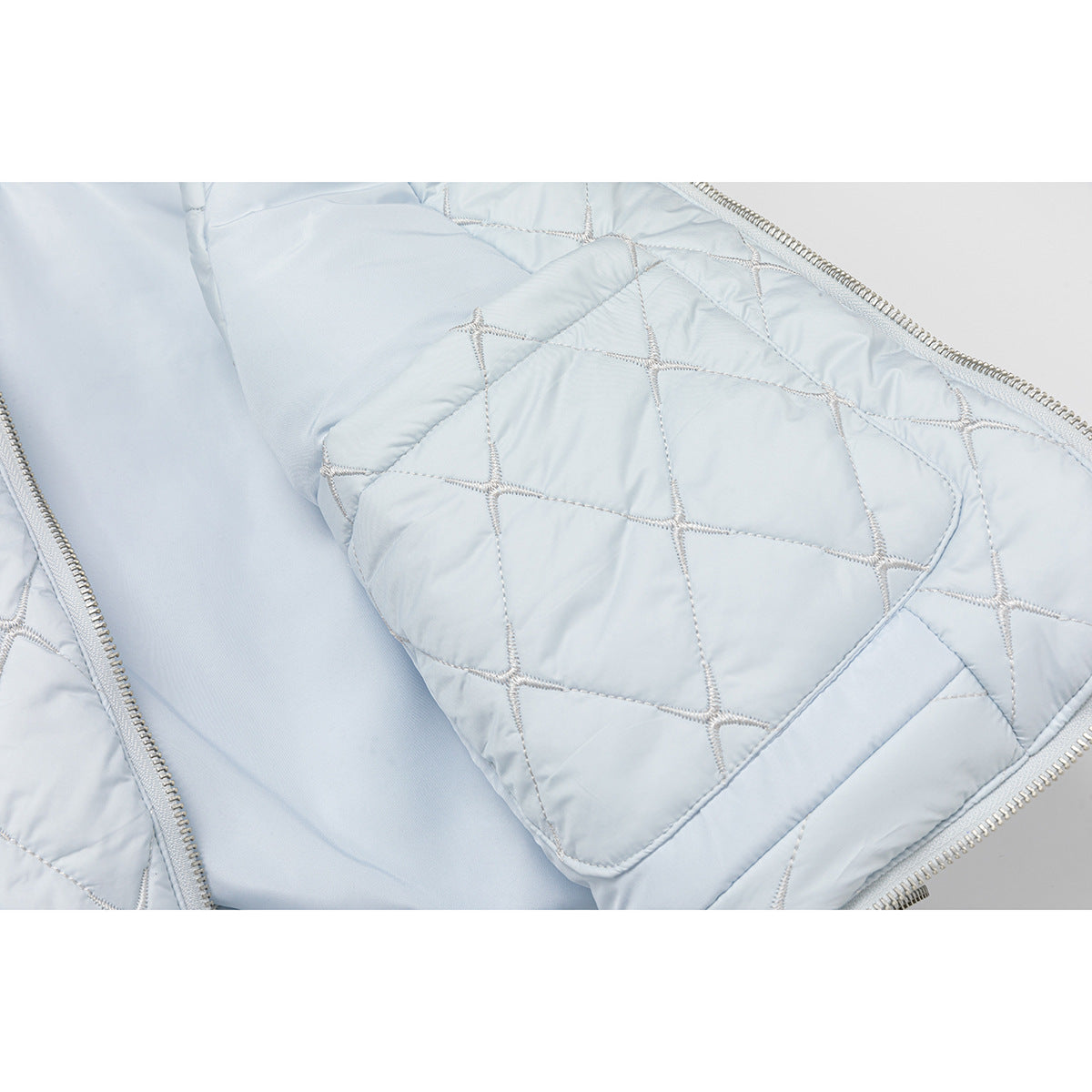Close-up of the pale blue vest's quilted interior, patch pocket, and zipper.