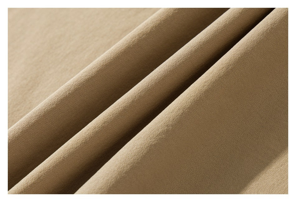 Extreme close-up of tan pant fabric arranged in soft folds.
