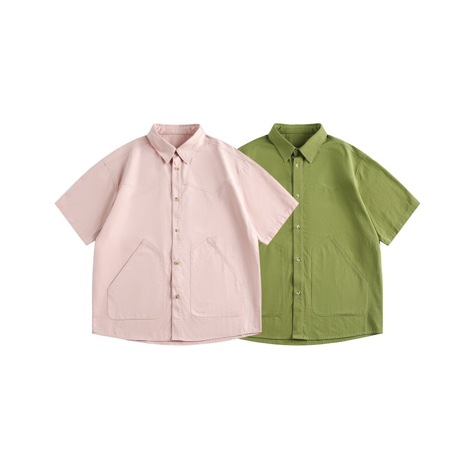Front views of short-sleeve collared button-up shirts in pale pink and olive green, each with two large pockets.