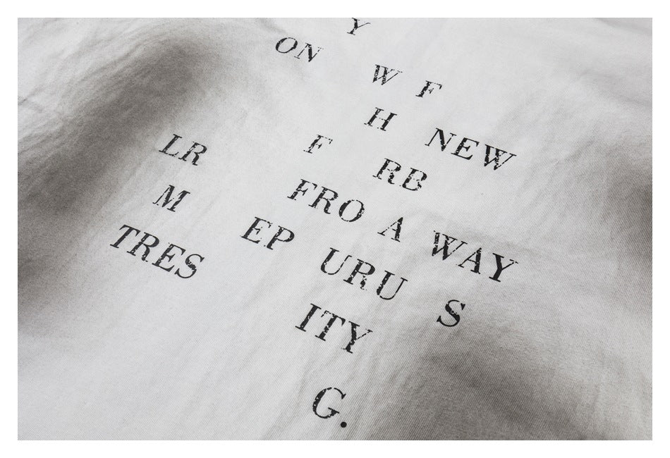 Close-up of scattered black English lettering printed on white fabric.