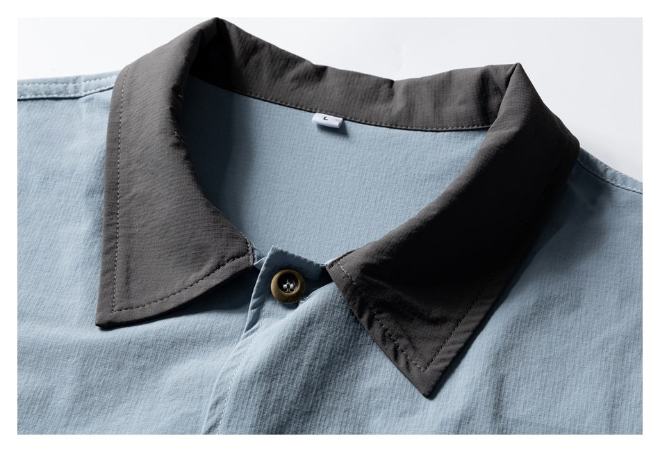 Close-up of a light blue shirt's charcoal pointed collar and brown button.