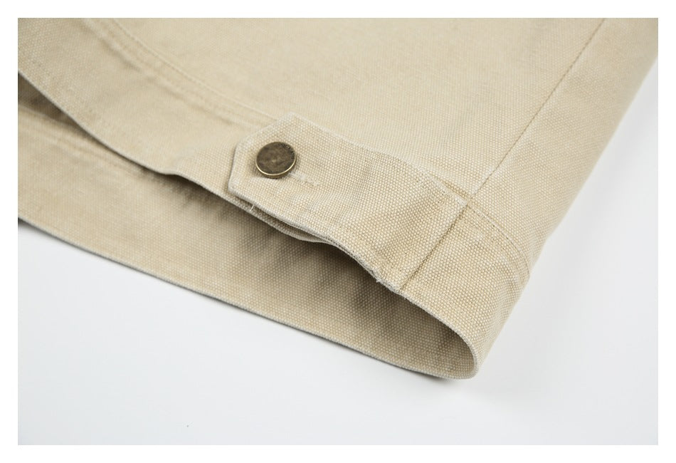 Close-up of a beige jacket hem with a buttoned side tab and stitched edge.