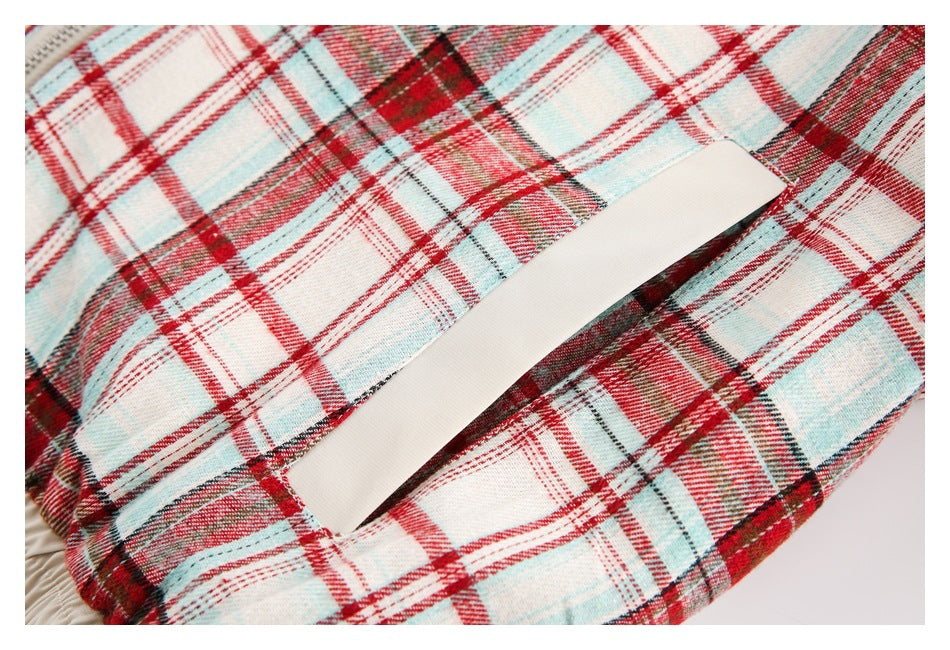 Close-up of a slanted pocket opening with a cream lining against red, cream, and pale blue plaid fabric.