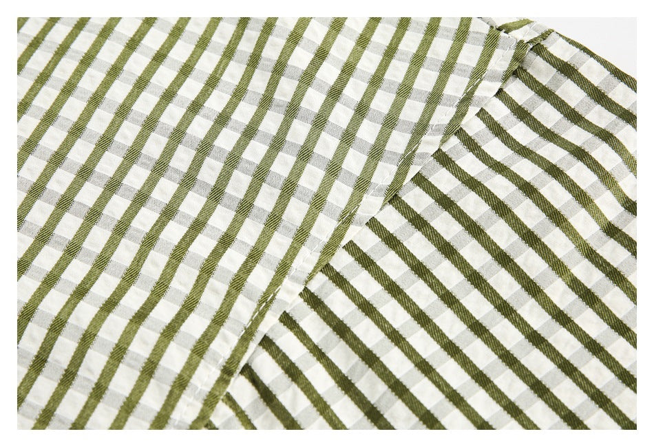 Close-up of olive stripes crossing a pale gray-and-white check pattern on a shirt.