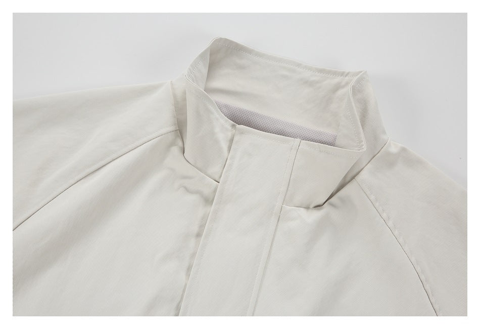 Close-up of an off-white jacket's high collar, mesh lining, and covered front closure.