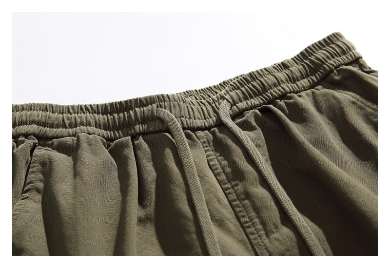 Close-up of olive shorts showing the gathered elastic waistband, drawstring, and stitching.
