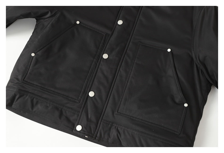 Close-up of a black jacket front with two large patch pockets and silver snap buttons.