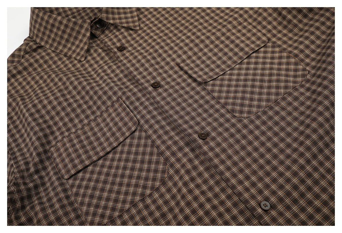 Close view of a brown plaid button-up shirt laid flat, showing its collar, button placket, and two flap chest pockets.