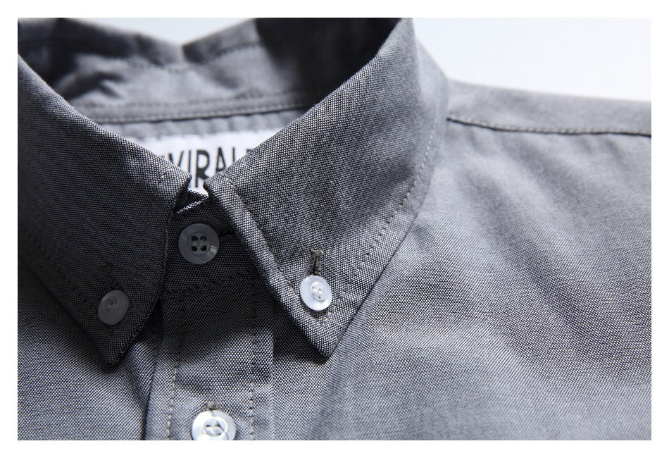 Close-up of a gray shirt's button-down collar, white buttons, and partially visible neck label.