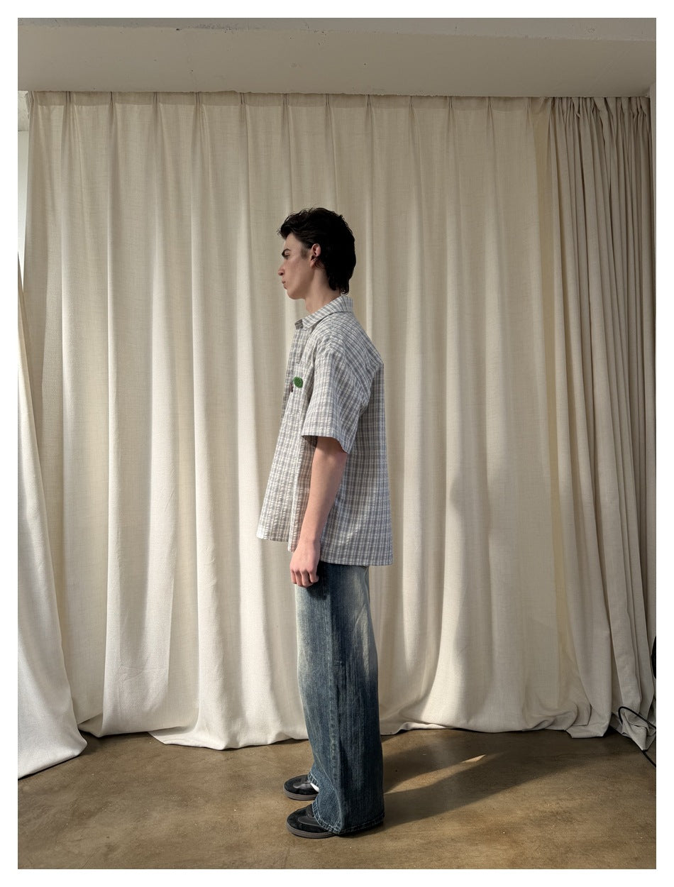 Side view of model wearing plaid short-sleeve shirt over a tee with wide-leg jeans