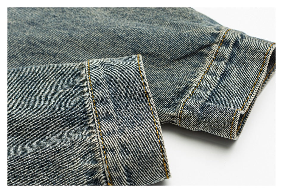 Close-up of overlapping blue denim hems with contrasting golden topstitching.