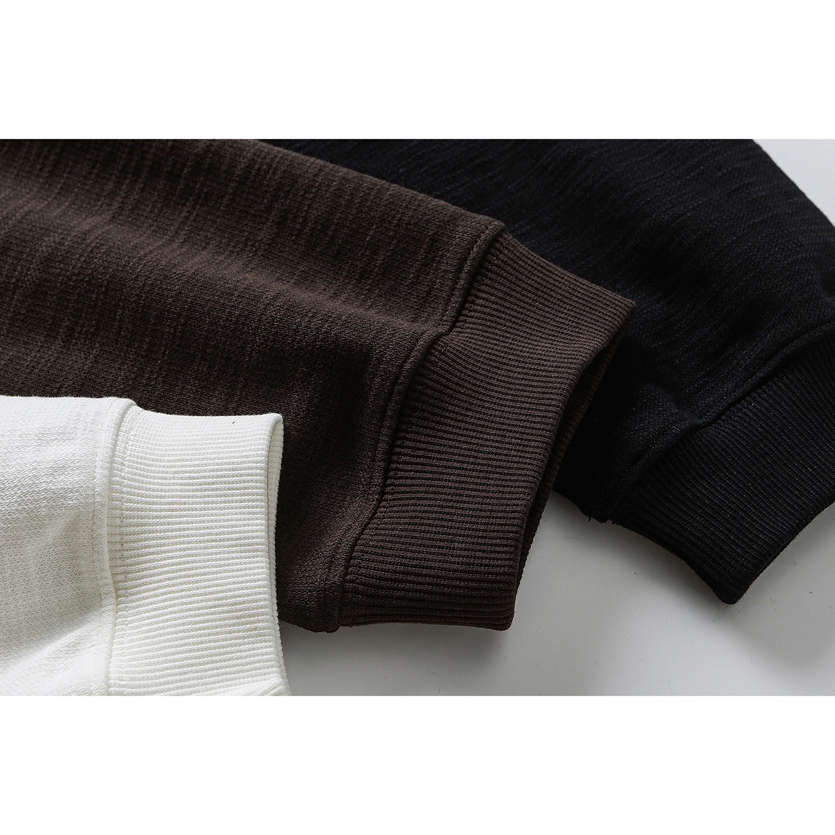 Close-up of ribbed sweatshirt cuffs in brown, black, and white.