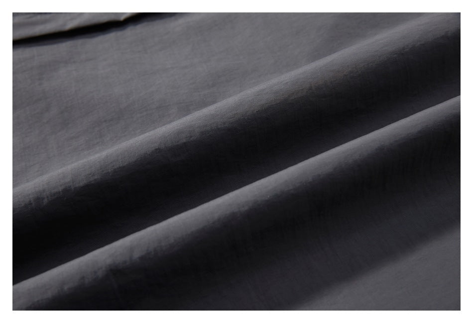 Macro view of dark charcoal garment fabric draped in folds, showing its surface texture.