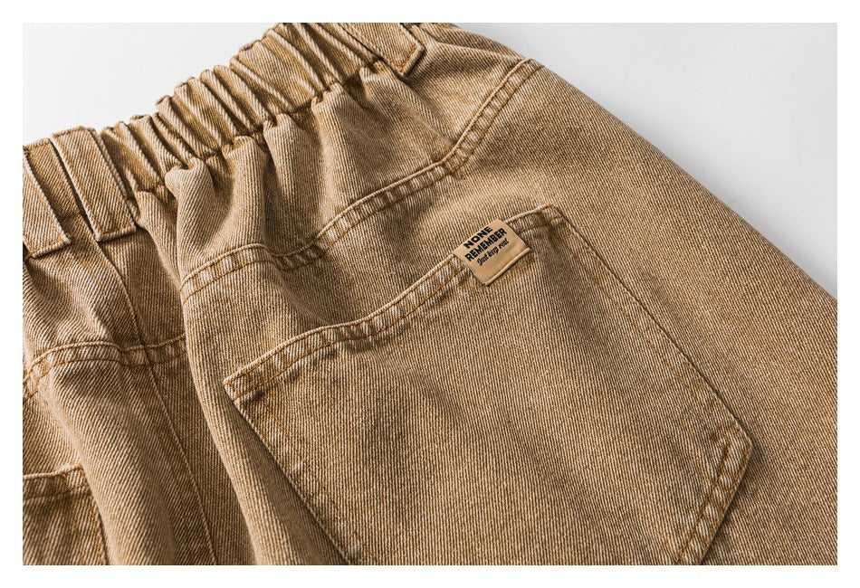 Close-up of brown pants showing the gathered elastic waistband, large pocket, and small sewn label.