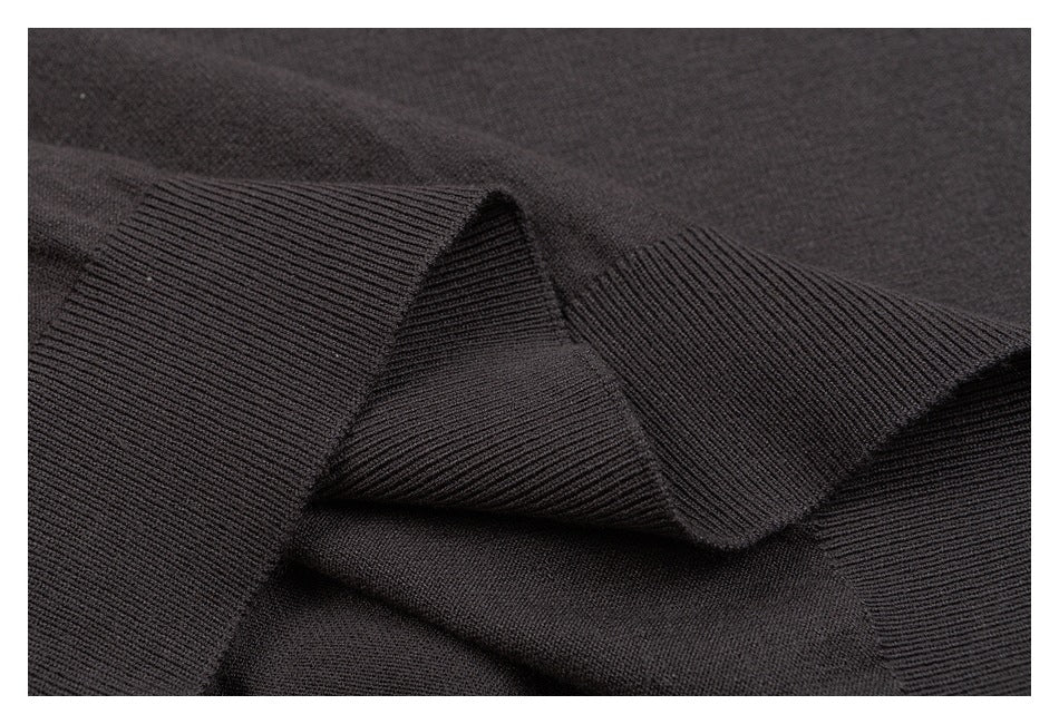 Close-up of overlapping ribbed knit edges on a dark charcoal garment.