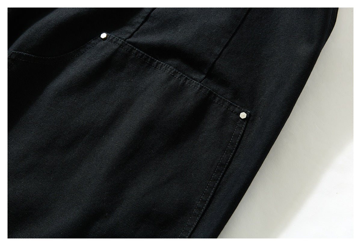 Close-up of a black trouser pocket with small light-colored rivets at the corners.