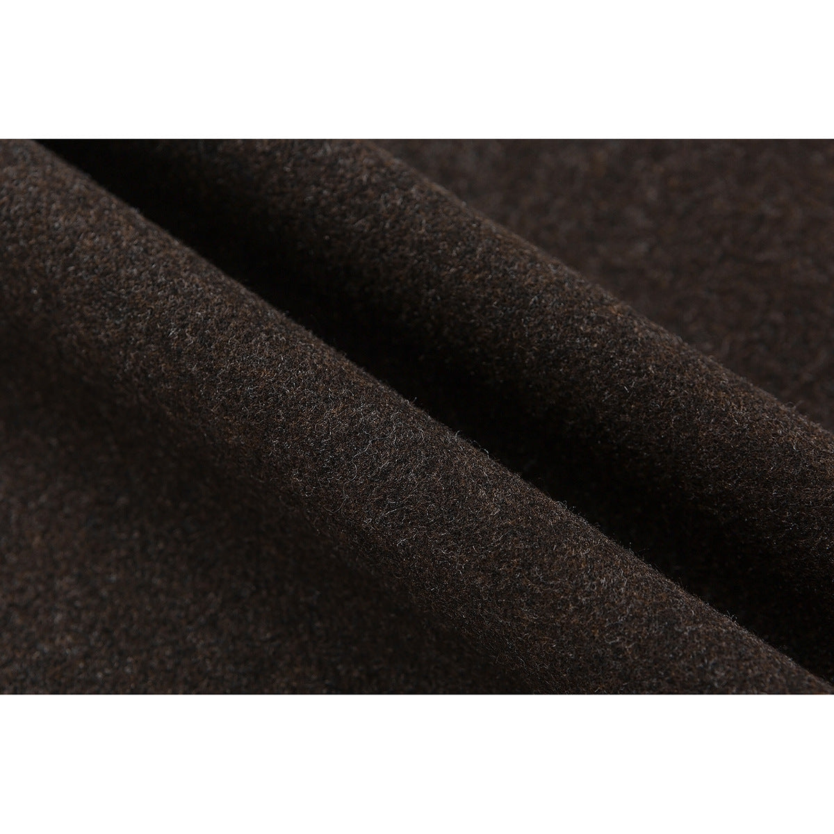 Extreme close-up of the dark brown pants' textured fabric and draped folds.