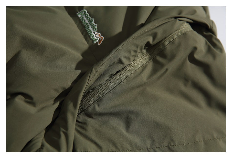 Close-up of an olive jacket with an embroidered logo and a diagonal zip pocket.