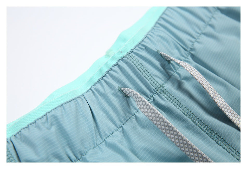 Close-up of a blue-green elastic waistband with two gray drawstrings.