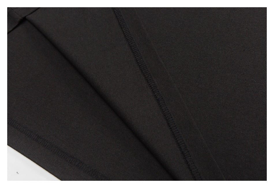 Close-up of black garment construction showing a long overlocked seam and stitched edge.