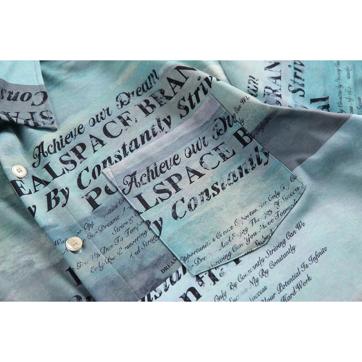 Close-up of the shirt's blue-toned English text print, pointed collar, pocket, and light-colored buttons.