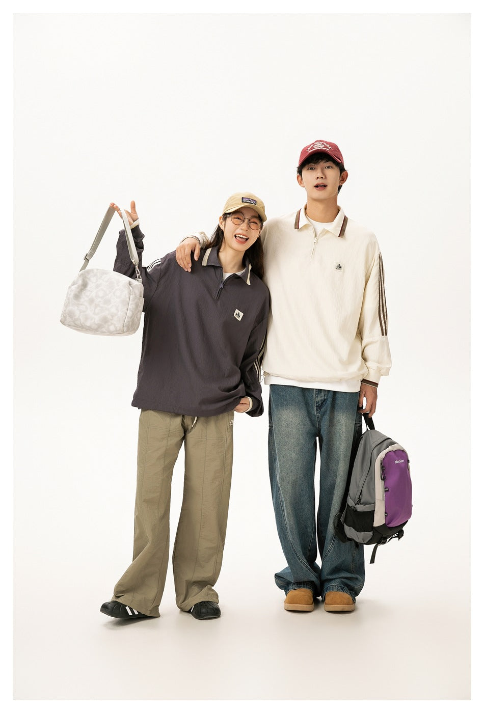 Two models pose together in oversized quarter-zip pullovers, one charcoal with cream stripes and one cream with brown